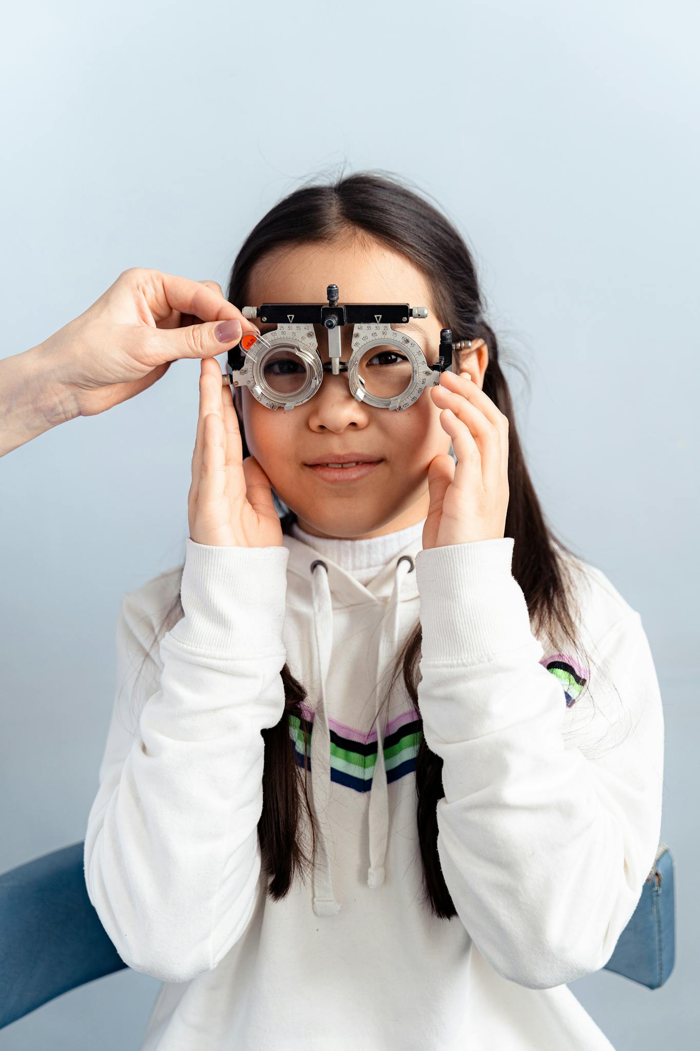 A young girl undergoing an eye test with a trial frame in an optometry checkup.